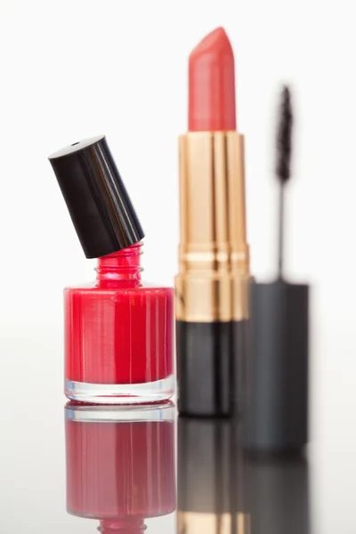 A mascara tube with a pale red lipstick and a red nail polish fl — Stock Photo, Image