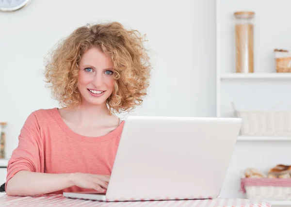 सुंदर सुनहरे बालों वाली महिला बैठे हुए अपने लैपटॉप के साथ आराम कर रही है — स्टॉक फ़ोटो, इमेज