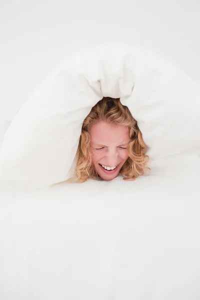Attractive blonde female balled-up in a duvet in her bedroom — Stock Photo, Image