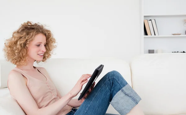 Charming blonde woman relaxing with her tablet while sitting on — Stock Photo, Image