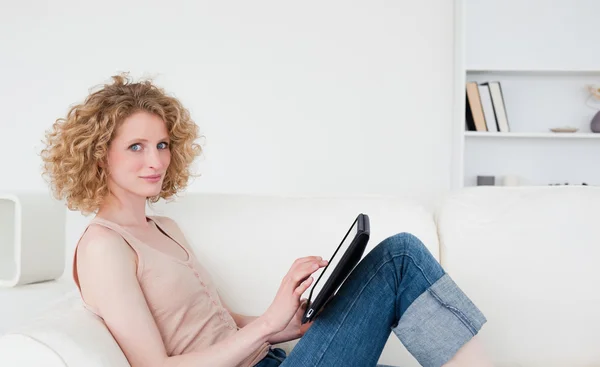 아름 다운 금발의 여 자가 그녀의 태블릿에 앉아있는 동안 편안한 — 스톡 사진