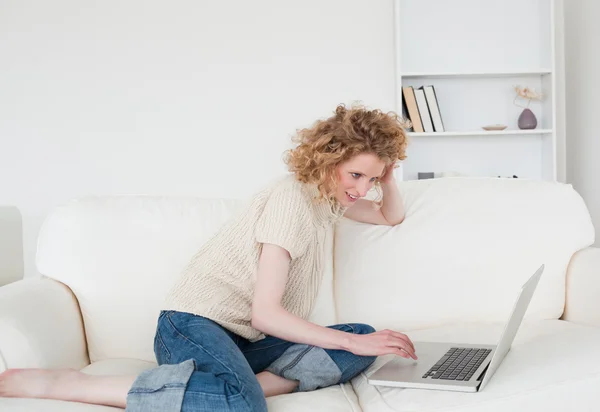 Mujer rubia bonita relajándose con su portátil mientras está sentada en un — Foto de Stock