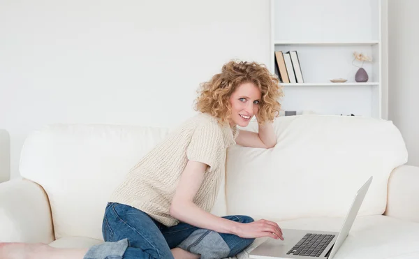 Encantadora mujer rubia relajándose con su portátil mientras está sentada en —  Fotos de Stock