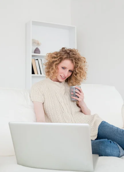 그녀의 노트북에 앉아있는 동안 편안한 화려한 금발 여자 — 스톡 사진