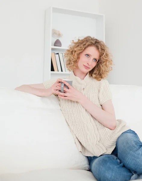 Atrakcyjny blond kobieta cieszyć się filiżanką kawy siedząc — Zdjęcie stockowe