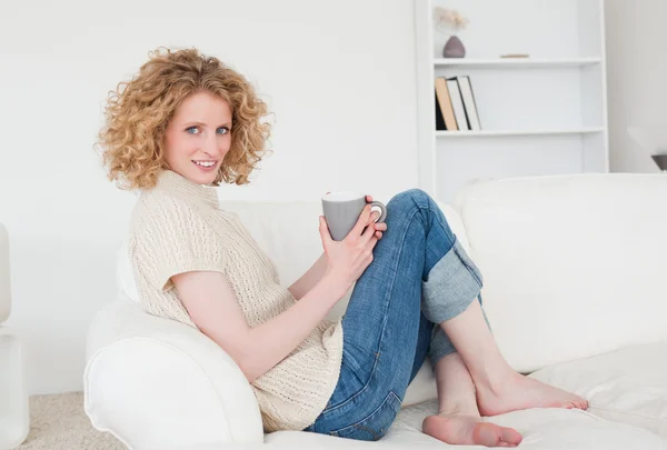 Lovely blonde female enjoying a cup of coffee while sitting on a — Stock Photo, Image