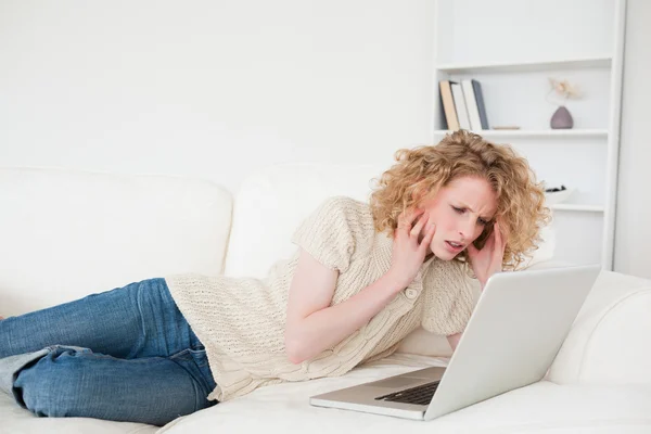 Przepiękny blond kobieta relaksując się przy jej laptop leżąc na — Zdjęcie stockowe