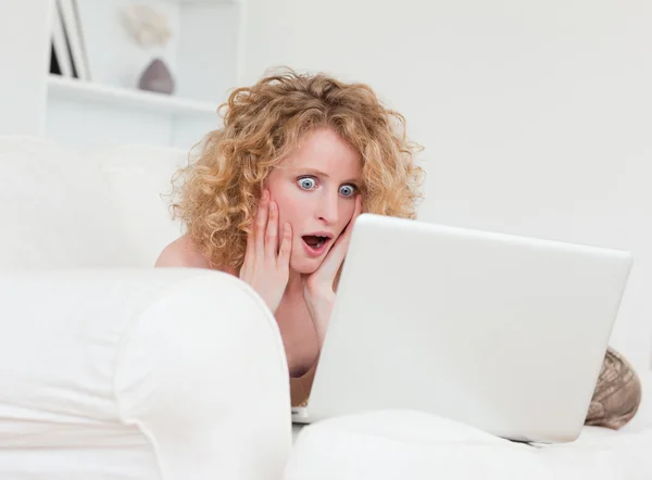 Aantrekkelijke verrast vrouwelijke ontspannen met haar laptop terwijl sitti — Stockfoto