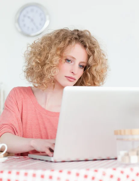 Mulher loira atraente relaxante com seu laptop enquanto sentado i — Fotografia de Stock