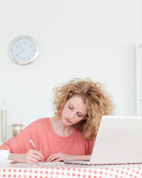 आकर्षक सुनहरे बालों वाली महिला अपने लैपटॉप के साथ काम करते समय लिख रही है — स्टॉक फ़ोटो, इमेज