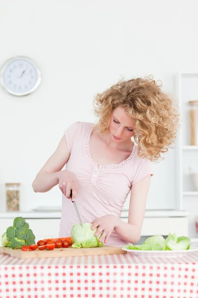Dobře vypadající blondýnka vaření nějakou zeleninu v kuchyni — Stock fotografie