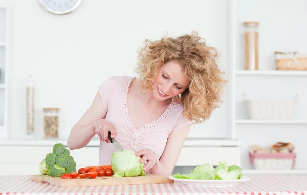 Affascinante donna bionda che cucina alcune verdure in cucina — Foto Stock