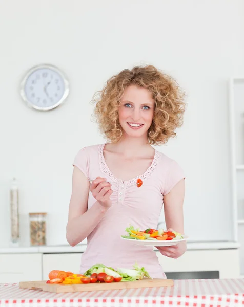 Atraktivní blondýnka, jíst některé zeleniny v kuchyni — Stock fotografie