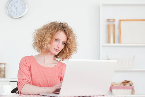 Чарівна блондинка розслабляється зі своїм ноутбуком, сидячи в — стокове фото