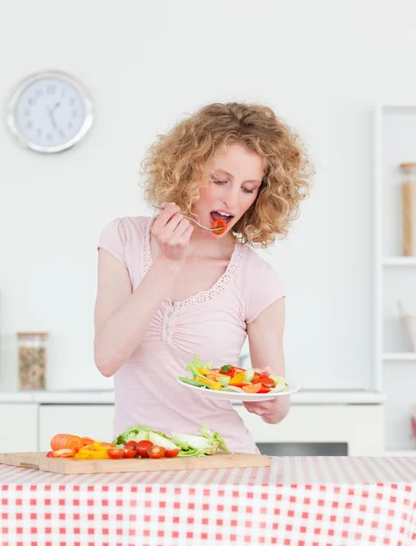 Mujer rubia bien parecido comer algunas verduras en la cocina — Foto de Stock