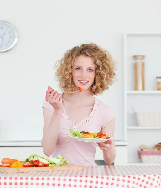 Ładny blond kobieta jedzenie niektórych warzyw w kuchni — Zdjęcie stockowe