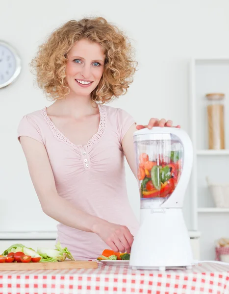 Pretty blonde woman using a mixer in the kitchen — Stock Photo, Image