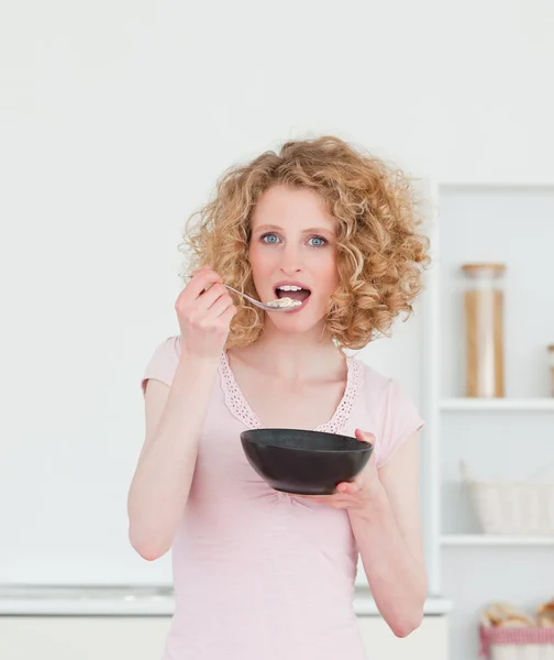 Mulher loira bonita comendo uma tigela de cereais na cozinha — Fotografia de Stock