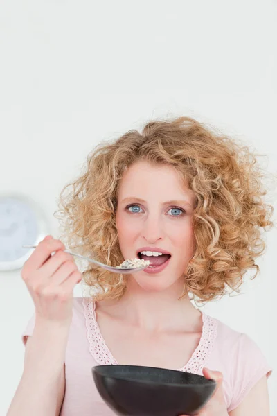 Atractiva mujer rubia comiendo un tazón de cereales en la cocina —  Fotos de Stock