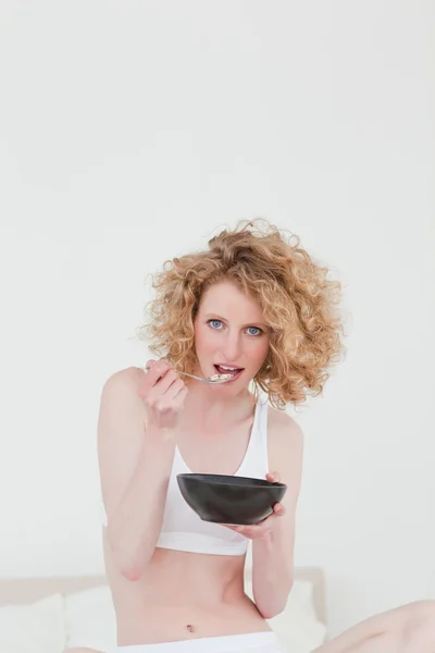 Underbara blonda kvinnan äter en skål med flingor medan du sitter på — Stockfoto