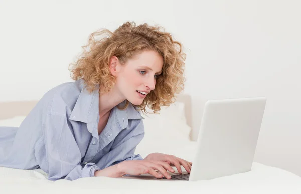 Linda mulher loira relaxante com seu laptop enquanto deitado sobre ele — Fotografia de Stock