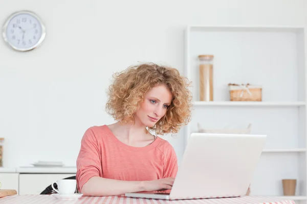 Femme blonde mignonne se détendre avec son ordinateur portable tout en étant assis dans le — Photo