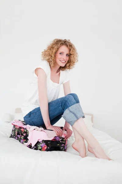 Hübsche blonde Frau versucht, ihren Koffer in ihrem Schlafzimmer zu schließen — Stockfoto
