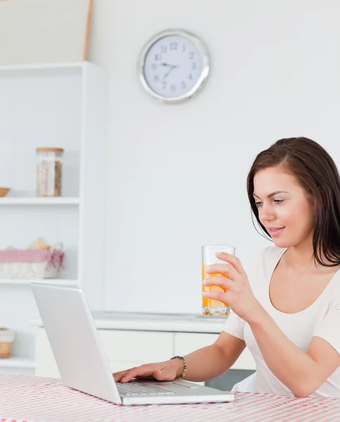 Portrait of a woman using her laptop and drinking juice — Stock Photo, Image