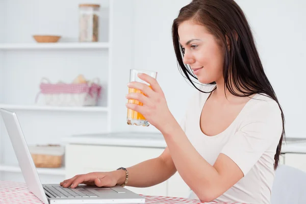 Close up of a woman using her laptop and drinking juice — Stock Photo, Image