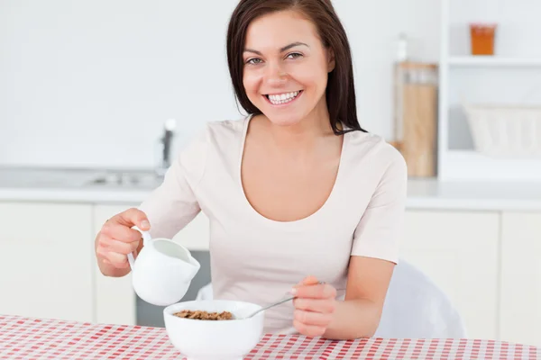 Young woman pouring milk in her cereal — Stock Photo, Image