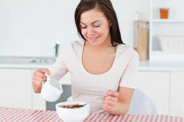 Brunette pouring milk in her cereal — Stock Photo, Image