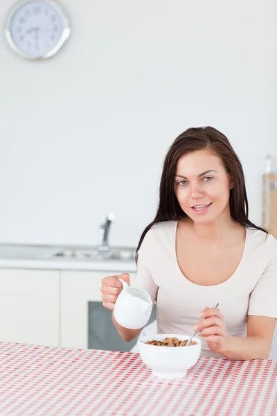 Retrato de uma jovem mulher derramando leite em seus cereais — Fotografia de Stock