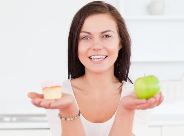 Mujer joven con una manzana y un pedazo de pastel — Foto de Stock