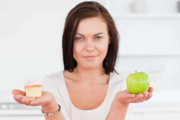 Morena encantadora com uma maçã e um pedaço de bolo — Fotografia de Stock