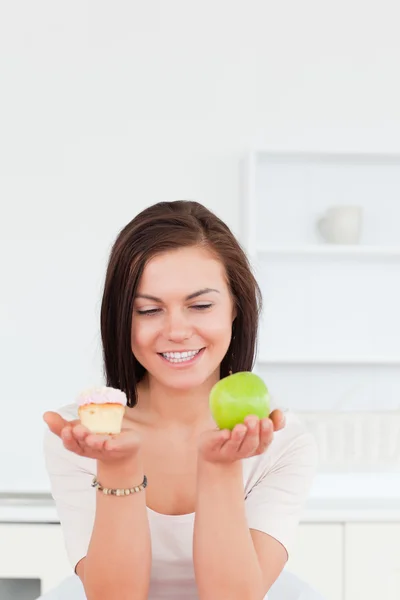 Retrato de uma morena encantadora com uma maçã e um pedaço de bolo — Fotografia de Stock