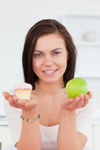 Portrait of a cute brunette with an apple and a piece of cake — Stock Photo, Image