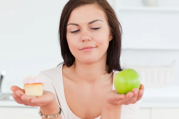 Primer plano de una guapa morena con una manzana y un trozo de pastel — Foto de Stock