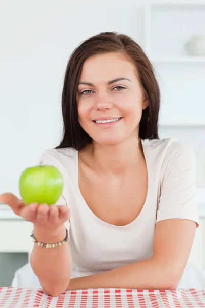Morena encantadora mostrando uma maçã — Fotografia de Stock