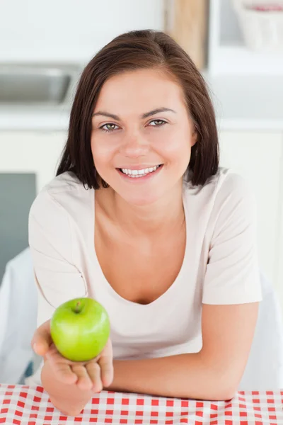 Skrattar brunett visar ett äpple — Stockfoto