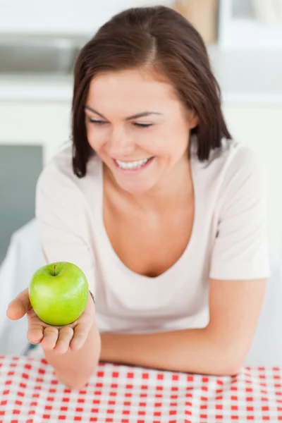 Γελώντας μελαχρινή κοιτάζοντας ένα μήλο — Φωτογραφία Αρχείου