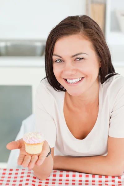 Śmiejąc się brunetka, Wyświetlono cupcake — Zdjęcie stockowe