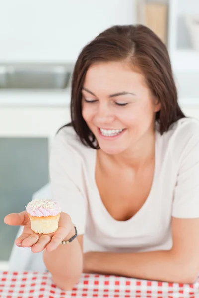 Laughing brunette looking at a cupcake — Stock Photo, Image