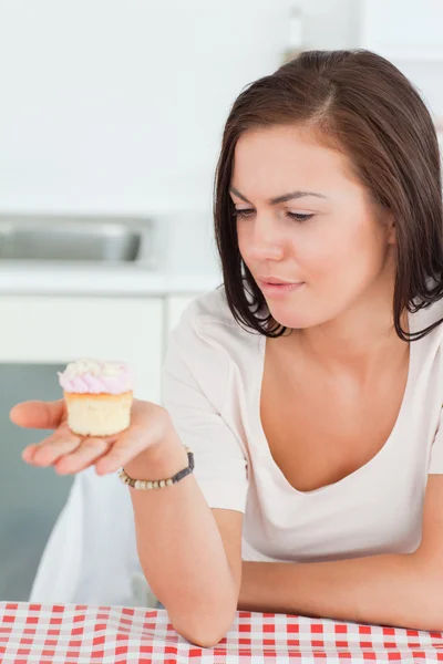 Linda morena mirando un cupcake — Foto de Stock