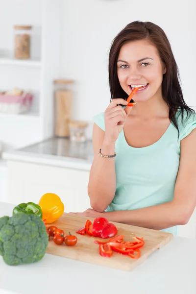 Cute brunette eating a slice of pepper — Stock Photo, Image