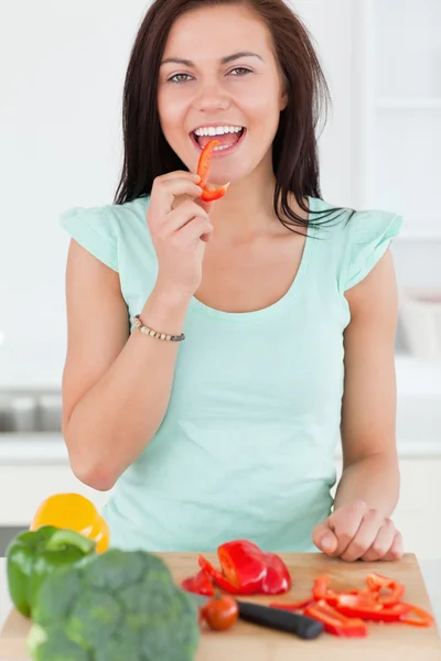 Portrait of a smiling woman eating a slice of pepper — Stock Photo, Image