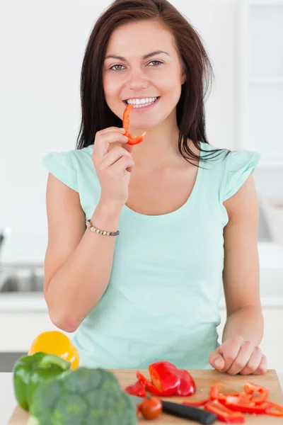 Retrato de uma mulher bonita comendo uma fatia de pimenta — Fotografia de Stock