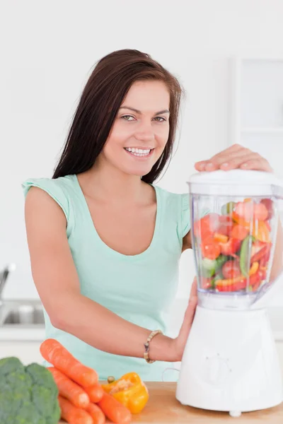 Charmante dunkelhaarige Frau mit einem Mixer — Stockfoto