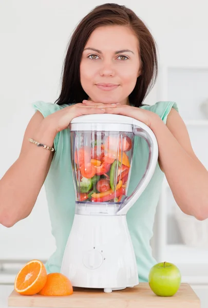 Smiling dark-haired woman posing with a blender — Stock Photo, Image