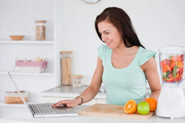 有一台笔记本电脑和水果在搅拌机的女人 — 图库照片
