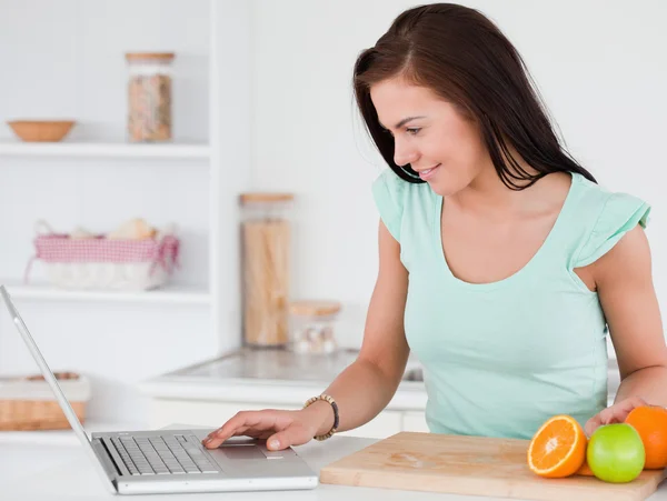 Mujer joven con un ordenador portátil y frutas — Foto de Stock